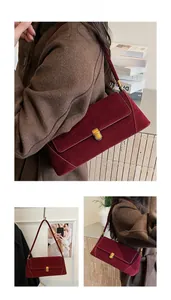 Dettaglio di una borsa baguette in camoscio bordeaux con chiusura e tracolla dorate