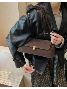 Dettaglio di una borsa baguette in pelle scamosciata marrone scuro con chiusura dorata