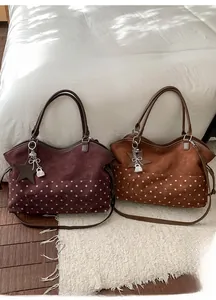 Detail of burgundy and brown suede tote bags with star charms and Muon Shark embroidery