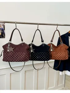 Detail of suede tote bag with polka dots, metal lock pendant and bow charm accessory