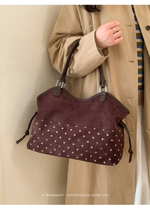 Detail of brown suede tote bag with white polka dots and embroidered letter branding