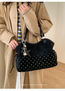Detail of black suede tote bag with white polka dots, star charm and bow chain detail