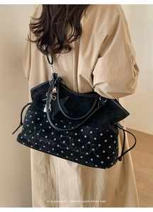 Detail of black polka dot suede tote bag with embroidery and star charm on a model