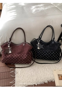 Close-up of suede tote bags with white polka dots and metal star charms on a bed