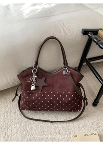 Detail of burgundy suede tote with white polka dots, embroidery, and star charm
