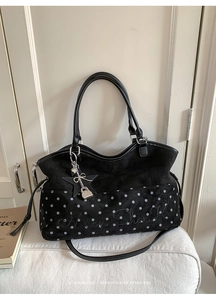 Detail of black suede tote bag with white polka dots, logo embroidery and star charm