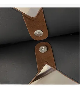 Close-up of circular magnetic clasp on grey lychee leather with brown suede accents