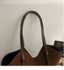 Detail of coffee brown suede tote bag featuring a V-shaped top and elegant knotted handles