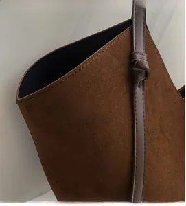 Detail of dark brown suede shoulder bag with fine stitching and knotted strap design