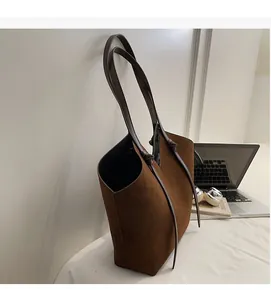 Detail of a large brown suede tote bag with soft fabric texture and dual long shoulder straps