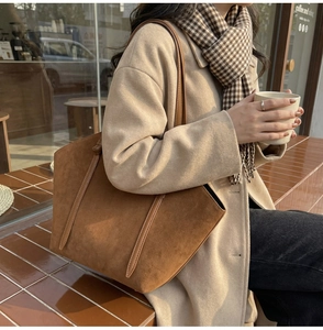 Minimalist brown suede tote bag carried by a model in an elegant autumn street style