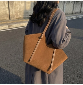 Detail of vintage caramel suede tote bag featuring smooth leather straps and metal base studs