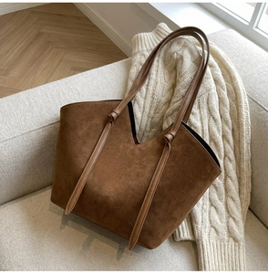Detail of dark brown matte suede tote bag on a soft beige fabric sofa background