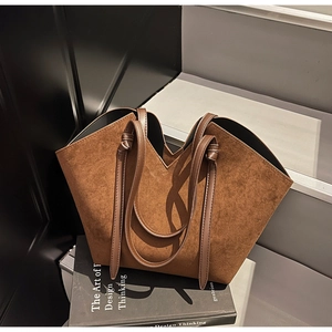 Detail of V-cut brown suede tote bag featuring fine stitching and knotted leather handles