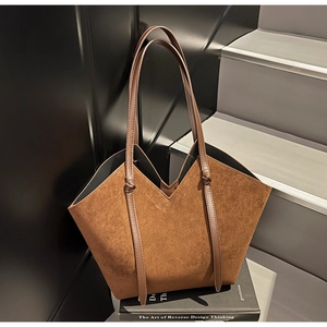 Macro view of brown suede-textured tote bag showing the deep V-shaped cut and knotted strap