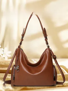 Close-up of brown litchi grain leather shoulder bag with side zippers and gunmetal hardware
