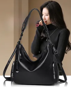 Detail of black pebbled leather hobo bag with side zippers and shoulder straps