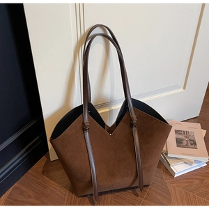 Detail of brown suede tote bag with unique V-cut opening and twisted strap accents