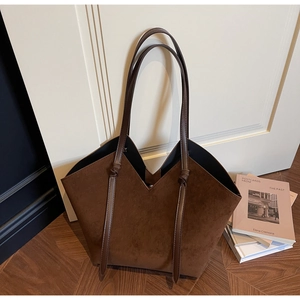 Detail of vintage brown suede tote bag with decorative knots and dual slim shoulder straps