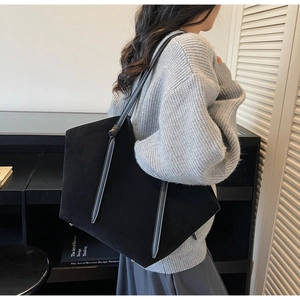 Detail of black suede tote bag featuring unique knotted leather handles and metal studs