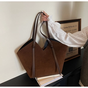 Detail of a large dark brown suede tote bag with decorative knots in a vintage setting