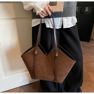 Close-up of a dark brown suede tote bag featuring a V-shaped top and knotted handle detail