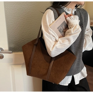 Detail of a dark brown suede tote bag with slim leather handles and vintage style