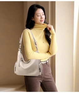 Detail of beige lychee grain hobo bag featuring metallic zipper and round charm