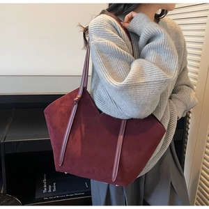 Detail view of wine red suede tote bag with V-shaped opening and protective metal feet
