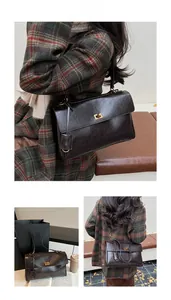 Detail of vintage oil-wax leather texture and gold twist lock on the brown shoulder bag