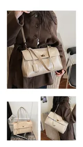 Detail of cream structured handbag with gold twist lock and adjustable shoulder strap