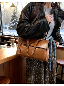 Detail of vintage brown leather bag with metallic twist-lock on a wooden counter