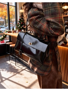 Detailed close-up of glossy black leather handbag with elegant gold metal twist lock buckle