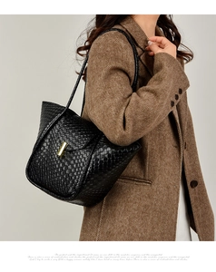 Dettaglio di un'elegante borsa tote nera intrecciata portata a spalla da una modella