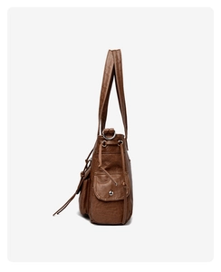 Détail d'un sac fourre-tout marron vintage avec plusieurs poches et fermeture à bouton argent