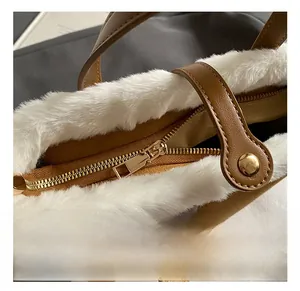 Detail of golden hardware zipper and white plush trim on brown faux leather handbag