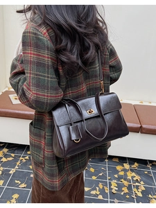 Detail of dark brown vintage faux leather shoulder bag with golden twist lock on model