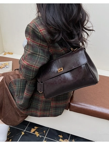Detail of vintage brown leather bag with golden square metal rotating lock and flap