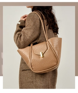 Dettaglio della borsa tote intrecciata marrone chiaro con chiusura dorata e pelle PU