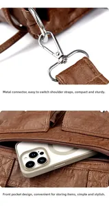 Détail du sac en cuir marron avec boucle en métal et poche avant contenant un téléphone