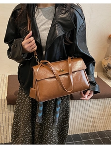 Close-up of retro brown oil-wax leather shoulder bag with metallic swivel lock detail