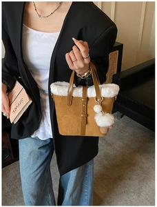 Close-up of brown suede bucket bag with white faux fur trim and decorative leather strap