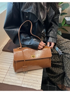 Detail of warm brown vintage leather handbag with metallic twist lock and slim strap