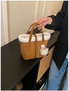 Detail of brown suede tote bag featuring white faux fur trim and gold buckle decoration