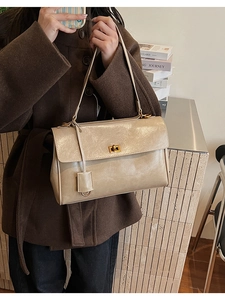 Detail of beige glossy leather shoulder bag with gold square twist lock and fine texture