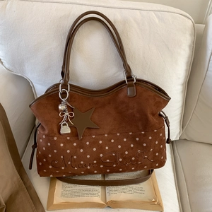 Brown suede tote bag with Moon Shark embroidery and star charms on a soft beige sofa