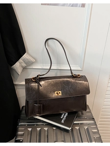 Macro detail of dark brown retro leather shoulder bag with gold twist lock and texture