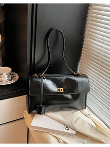Close-up of black glossy leather bag with golden twist lock and vintage oil wax texture