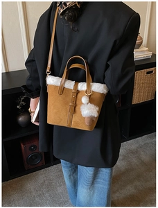 Brown suede crossbody bag with faux fur trim shown in a lifestyle indoor setting