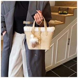 Close-up of beige frosted leather bucket bag with white faux fur trim and glove charm